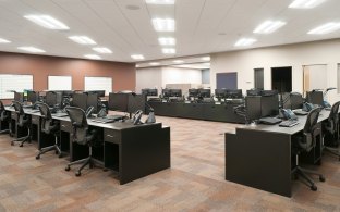Workstations in a central work area with black desks and chairs.