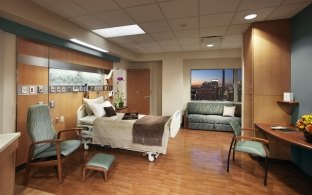 A patient room in the hospital tower with a bed on the left side and desk on the right side