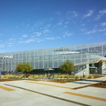Entrance and front of the rehabilitation center structure that features a blue sky and the parking lot