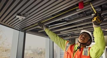 employee measuring something on the ceiling