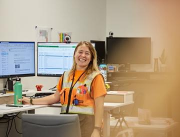 Person at a desk smiling at the camera.