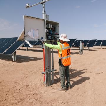 A person looking at an electrical component of a renewable energy project