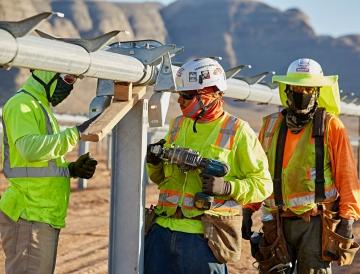 Three people working on the structure that will hold solar panels