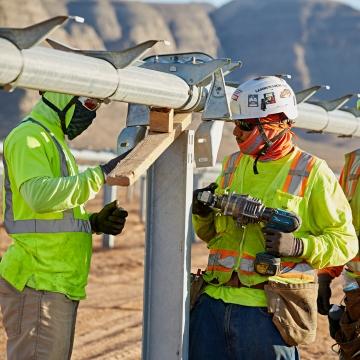 Three people working on the structure that will hold solar panels