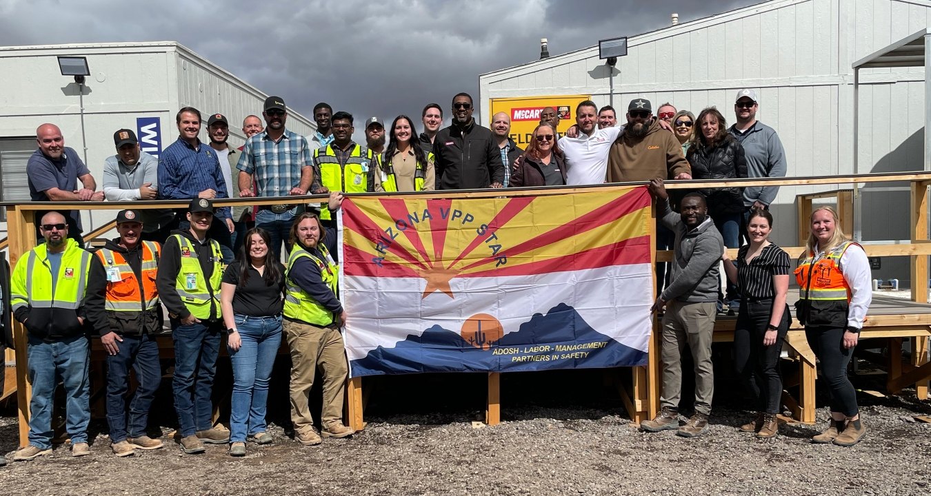 group of construction workers standing behind a flag