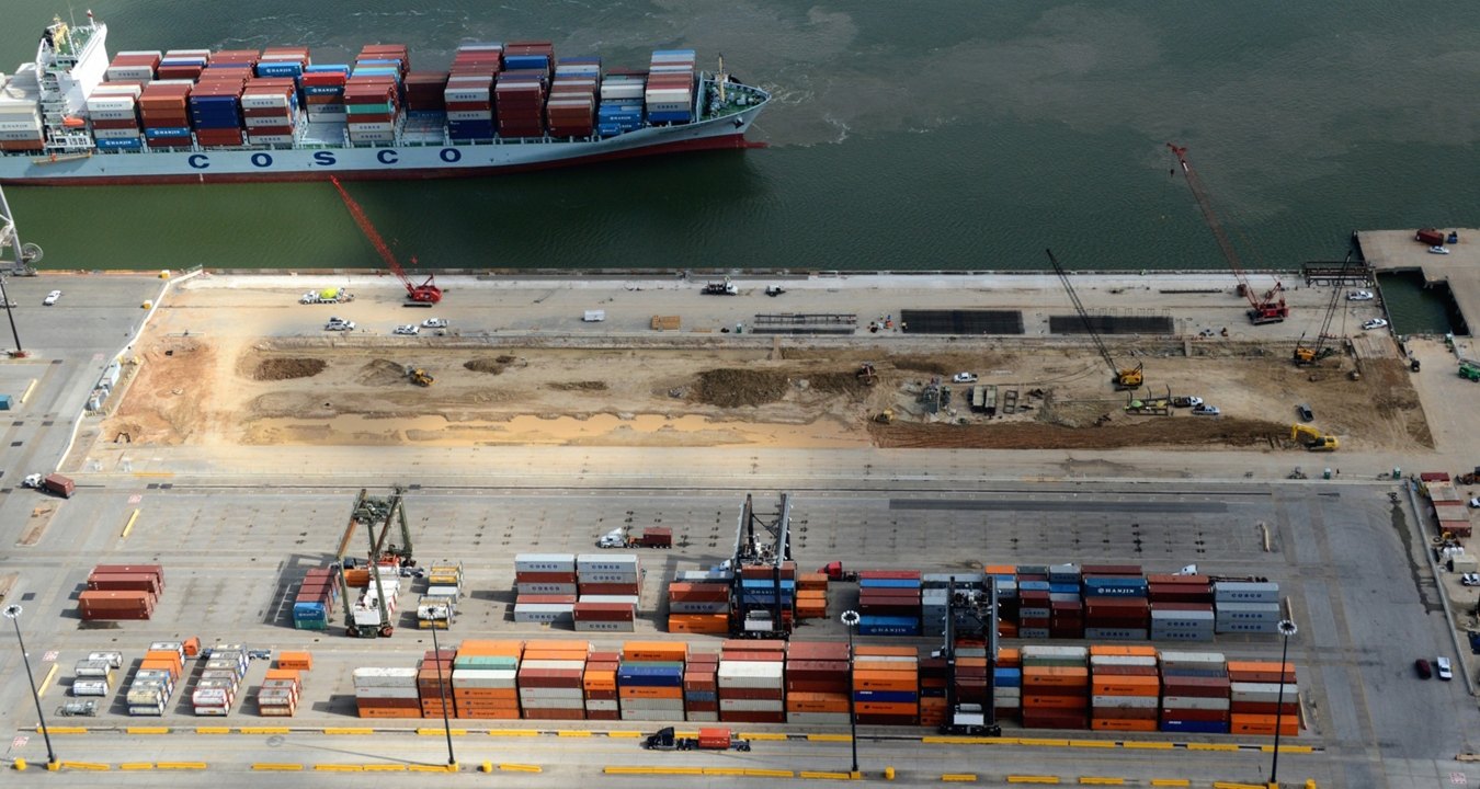 Aerial view of the site during construction with a ship on the water in the background