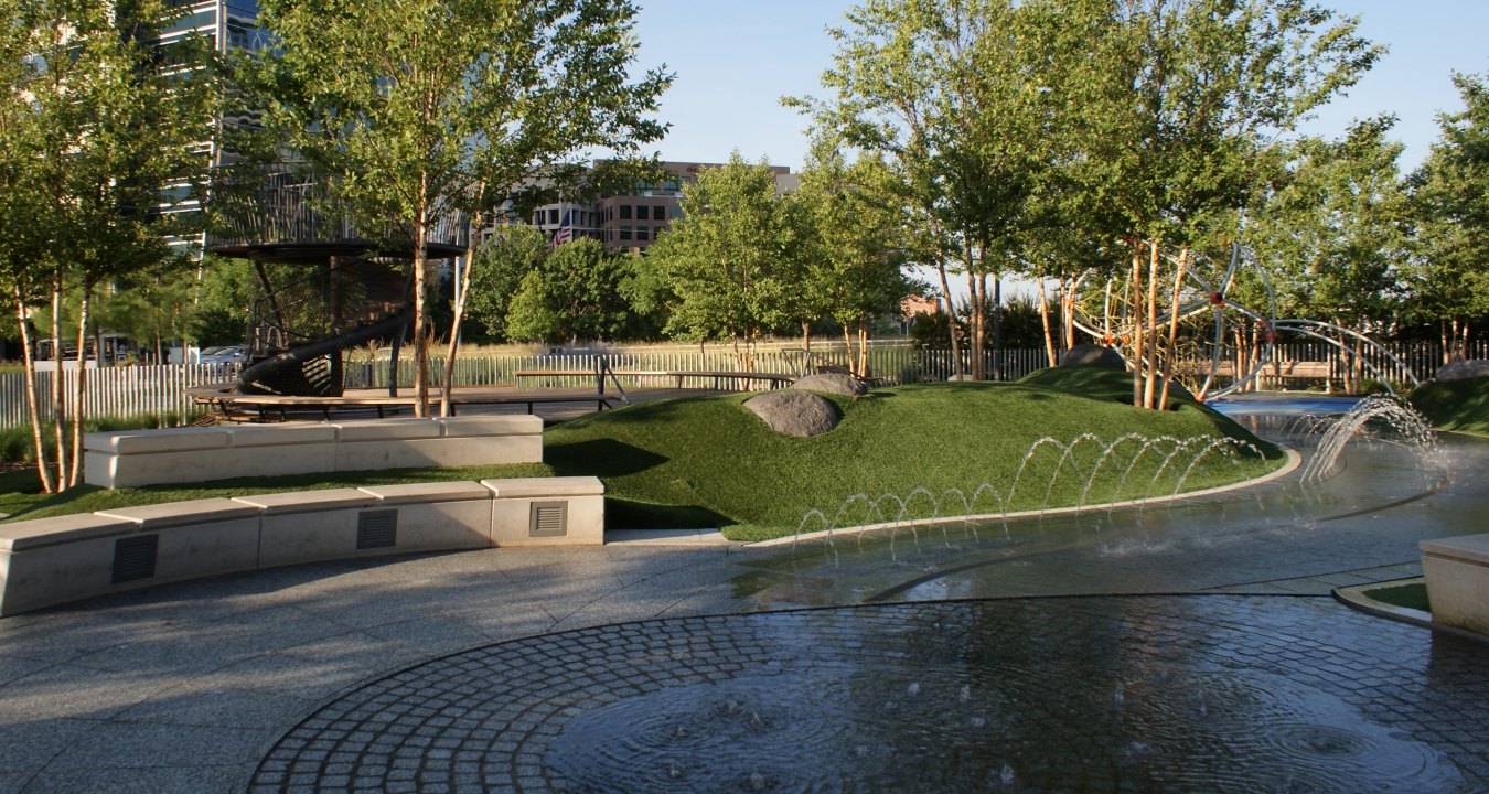 A fountain, bench, and greenery area at the park