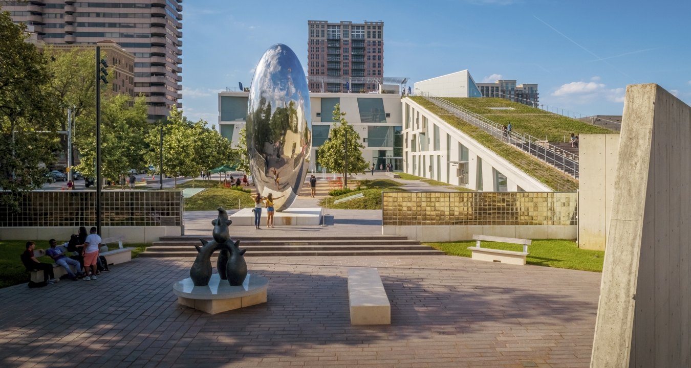 Outdoor image of the fine art park with people walking on concrete surrounded by grass