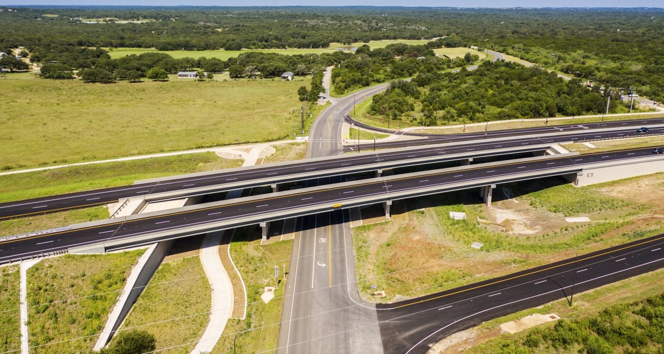 Highway with lots of greenery around and road going under