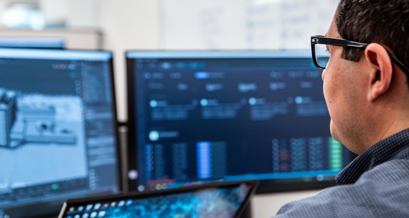 Person sitting at his desk looking at his monitors.