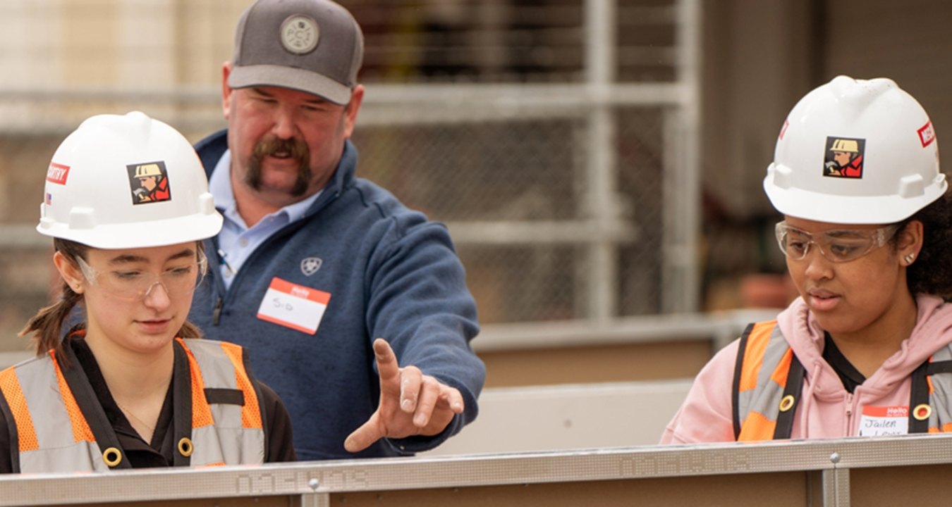 Two people learning from someone else during a Construction 101 event. 