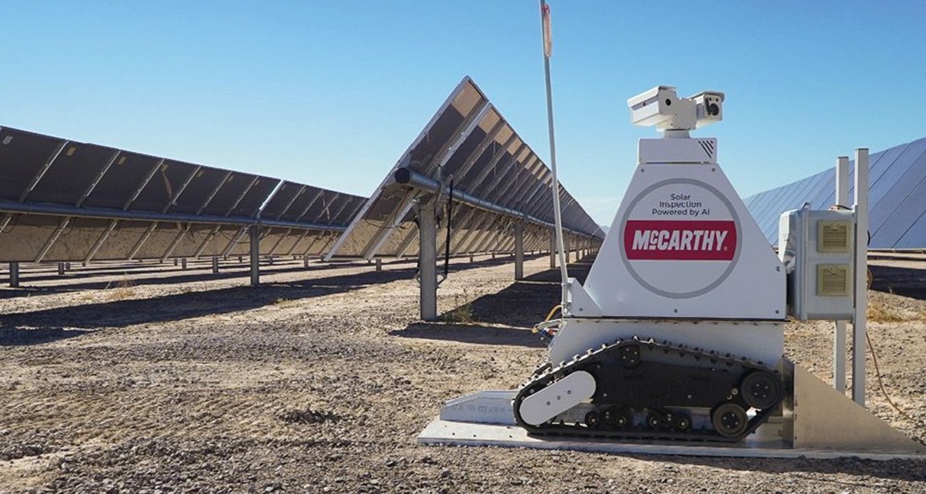 A robot in front of a few rows of solar panels