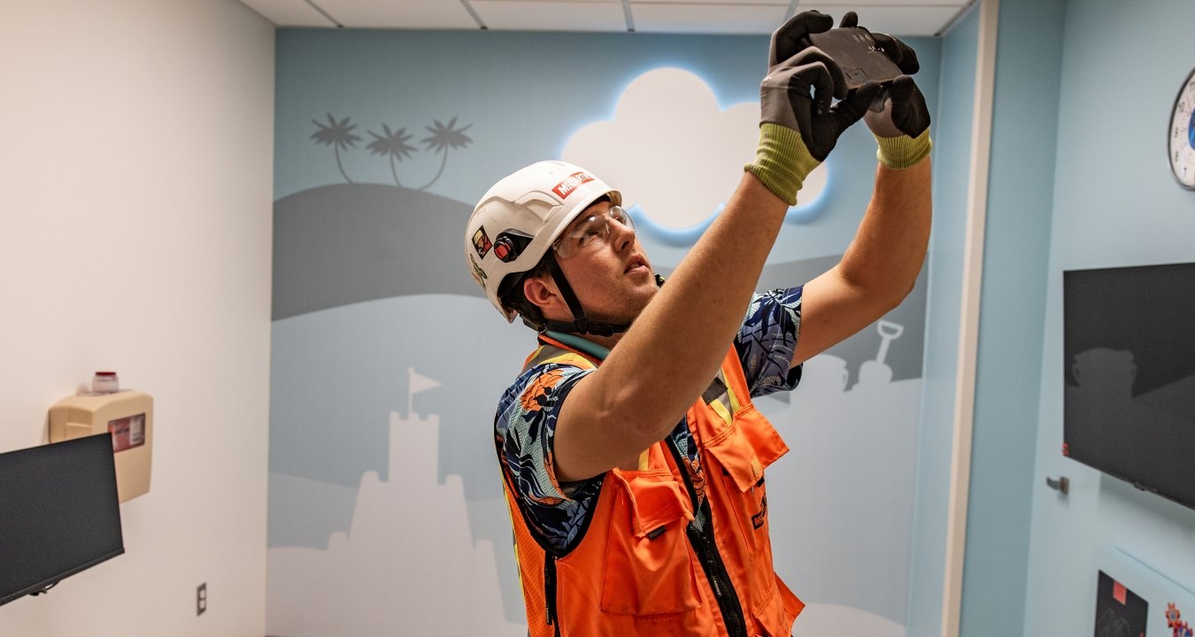A person wearing PPE taking a photo in a hospital room
