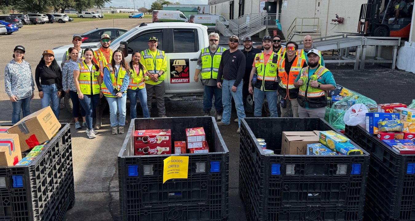 A group of people standing near a few cases of donated food items
