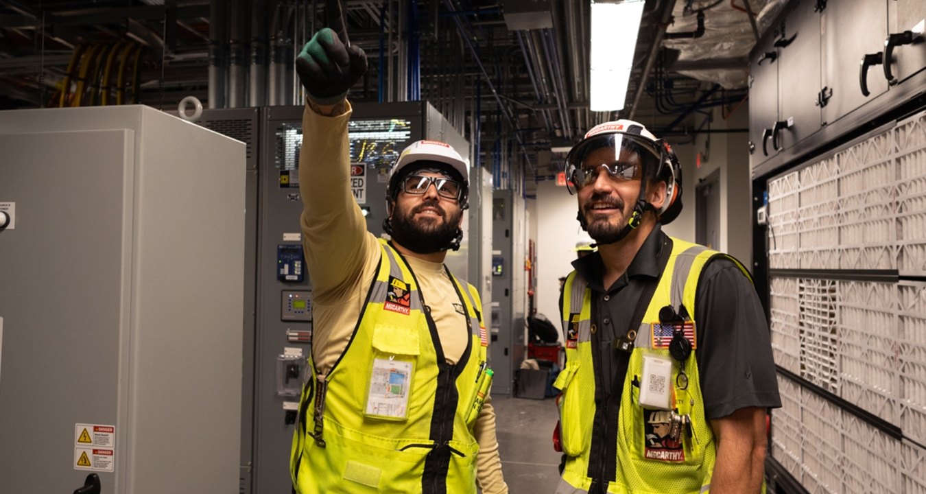 Two people wearing PPE and pointing