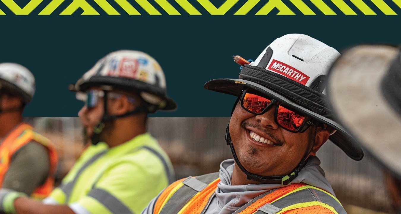 A person wearing PPE and smiling at another person.