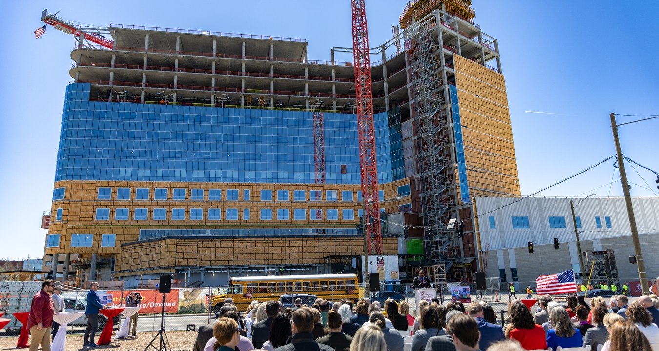 A group of people seated outside the hospital under construction