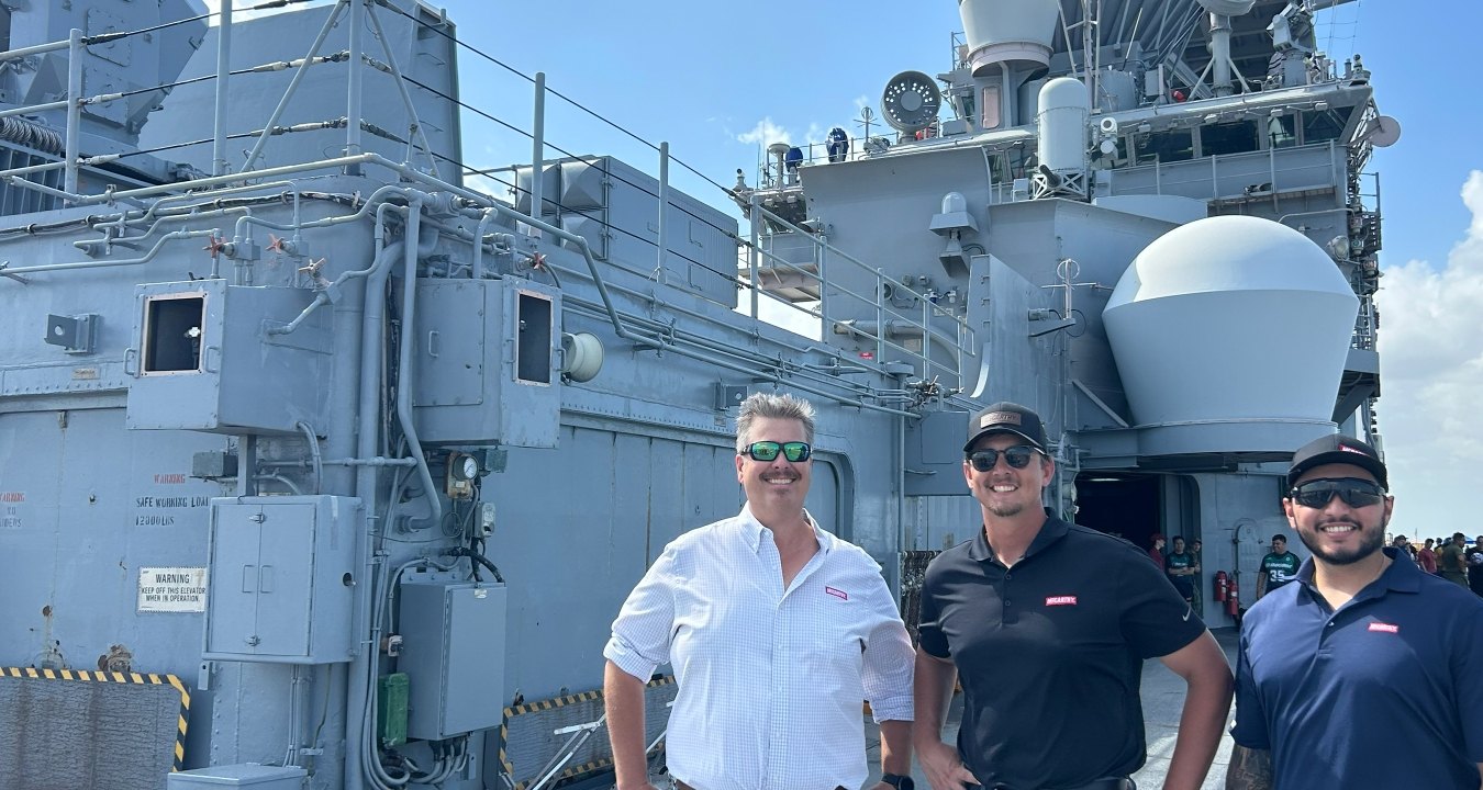 Three people standing in front of a military ship
