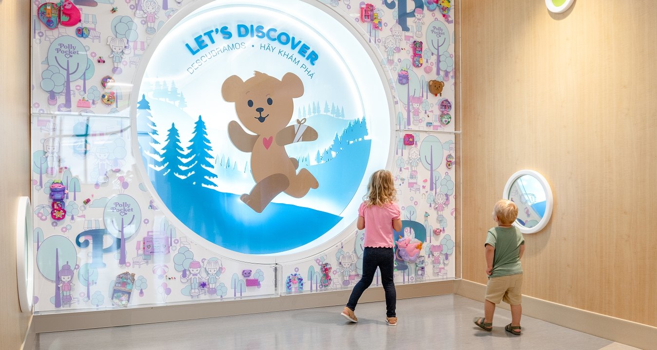 Two children looking at a sign that says "Let's Discover"