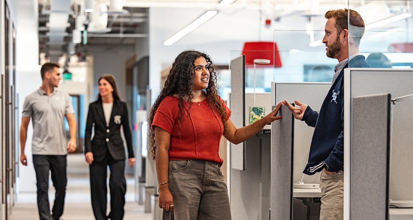 People standing and talking near a desk