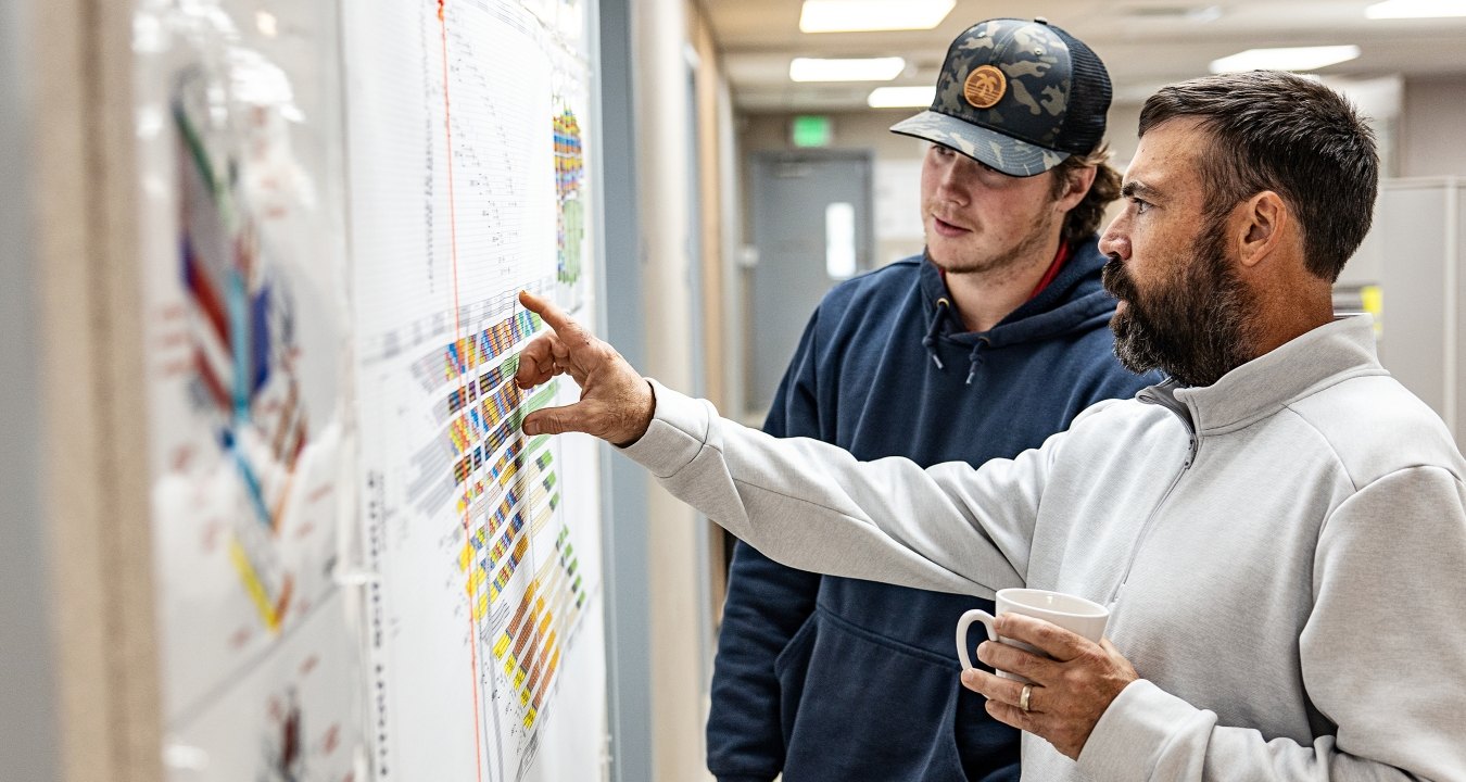 Two people looking at paperwork on the wall. 