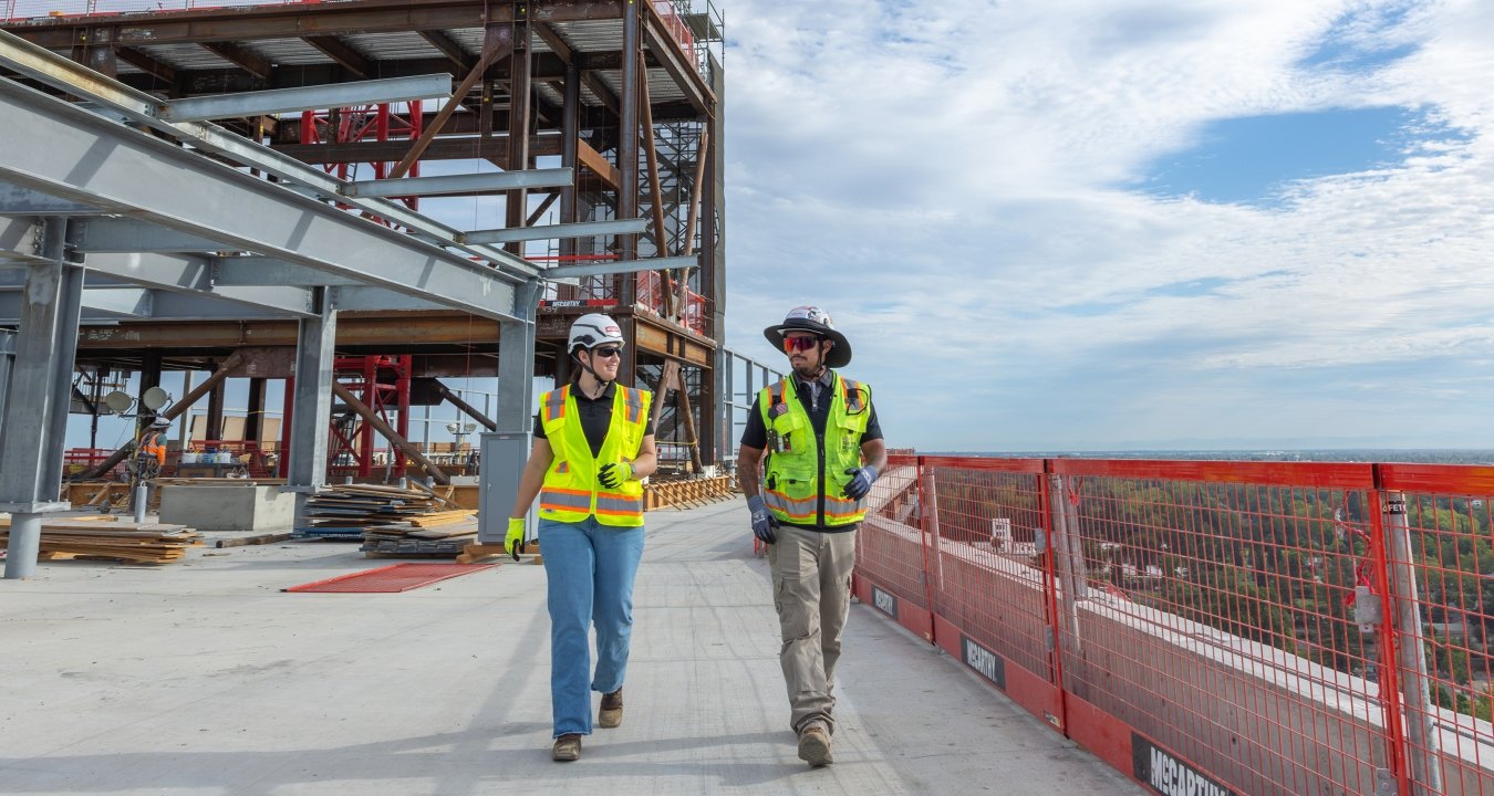Two people walking on a jobsite wearing PPE