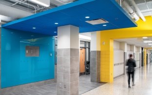 A student passes by hallway doors painted blue and yellow.