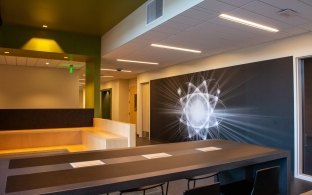 Rectangular table with chairs in a room with wall art on the righthand wall.