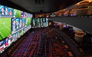 Two-story open seating area with multiple large screens on one wall