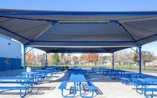 A covered outdoor seating area with multiple picnic tables.