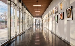 A hallway with large glass windows on one side and art on the opposite wall.