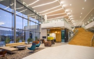 An open area with large glass windows, lounge chairs and a staircase.