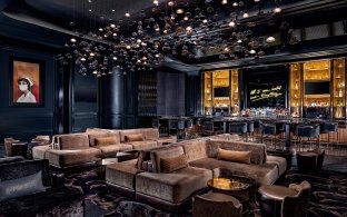 A lounge area with couches and tables, a dark setting, and an artistic ceiling piece