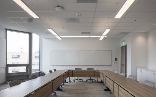 Classroom with long rectangular tables and chairs. 