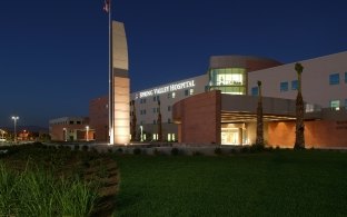 Exterior view of the hospital at nighttime, with landscaping in the foreground