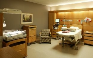 A patient room with a bed and chair. 