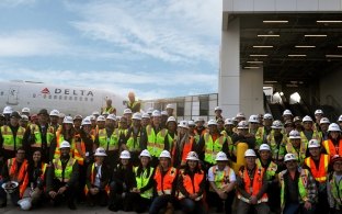Group photo of construction workers in front of Delta plane at LAX