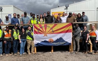 group of construction workers standing behind a flag