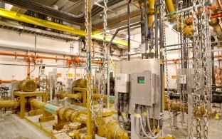 Interior control room inside a water treatment plant with pipes and gauges.