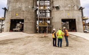 Three people standing outside dry fly facility