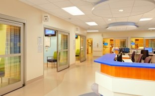 A hallway with patient rooms on the left and nurses' station on the right