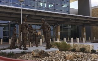 Exterior view of the hospital entryway with a statue in front