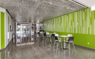 Open area with high top tables and chairs and a green wall in the background
