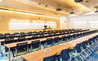 Classroom with long rectangular tables and chairs. 