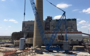 Outdoor image with blue skies and clouds with a blue crane moving building materials 