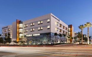 Outdoor image of the entire medical center with parking and palm trees