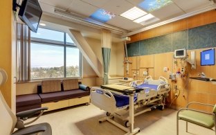 Indoor image of a patient room complete with the bed, tv and monitors