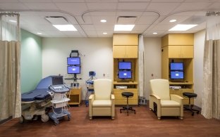 A patient area with a bed, chair, and desk with computer