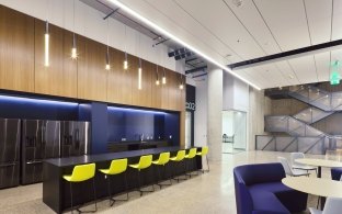 Kitchen area with tables, chairs and three big refrigerators 