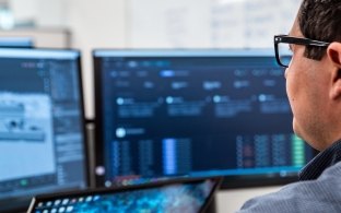 Person sitting at his desk looking at his monitors.